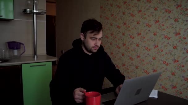 Jovem freelancer de sucesso trabalha em um laptop, bebe café e corrige seu cabelo — Vídeo de Stock
