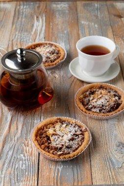 Ev yapımı fındıklı tart ve bir fincan siyah çay ile sade ahşap masada bal. 