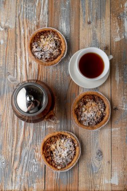 Ev yapımı fındıklı tart ve bir fincan siyah çay ile sade ahşap masada bal. 