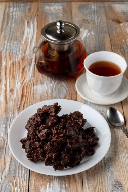 Kuru meyveli mısır gevreği, kuru meyve ve kuru üzümlü kurabiye ve eski ahşap masada bir fincan siyah çay.