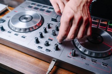 DJ kumandanın düğmelerini kapatıyor, erkek elleri görünür.
