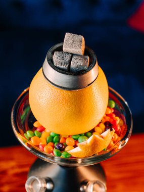 Turuncu nargile kasesinin üst görüntüsü etrafında şekerlemeler, tropikal portakal shisha yakın