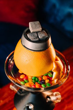 Turuncu nargile kasesinin üst görüntüsü etrafında şekerlemeler, tropikal portakal shisha yakın