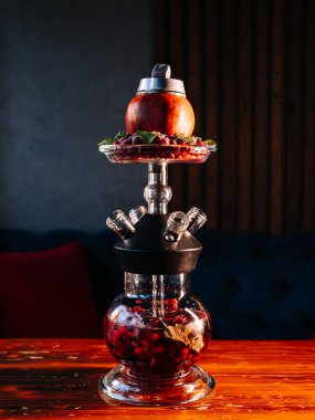 Nar nargile, çilek suyu ve olgun nar. Koyu bar odasındaki ahşap masanın üzerinde tütün kasesi gibi.