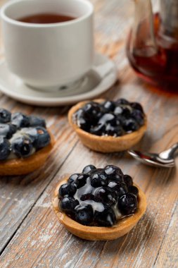 Kremalı ve yaban mersinli ev yapımı tartlara yakın. 