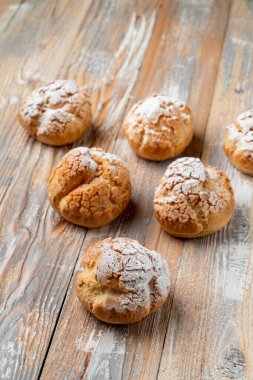 Kaliteli ahşap masaya tereyağlı kremayla doldurulmuş altın kabuklu profiterol.