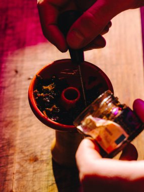 Nargile hazırlamak, kil kasesini tütünle doldurmak, erkek eli görünür.