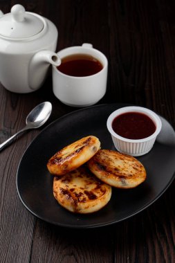 Kızarmış Rus süzme peynirli köfteleri siyah tabakta, tahta masada.