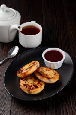 Kızarmış Rus süzme peynirli köfteleri siyah tabakta, tahta masada.