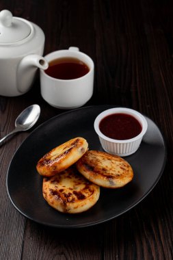 Kızarmış Rus süzme peynirli köfteleri siyah tabakta, tahta masada.