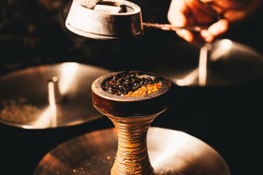 Shisha kasesine soğuk kömür küpleri koymak, erkek ellerine yakın durmak. 