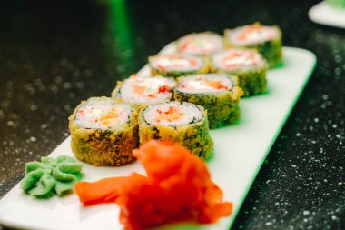 Krem peynirli kızarmış suşi ve beyaz tabakta çıtır çıtır nori.