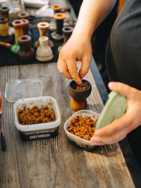 Shisha-man, nargile kasesini ıslak sarı tütünle doldurup konteynırdan alıyor.