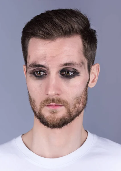 Das vertikale Porträt eines jungen Mannes mit schmutzigem Make-up. Traurig, den Blick nach unten gerichtet. Bart und Schnurrbart — Stockfoto