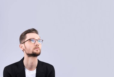 Gözlüklü genç bir adam yakından bir şeye benziyor. Şık görünümü, bıyık ve sakal. Bir şey hakkında düşünmekten ya da bir şey seçme