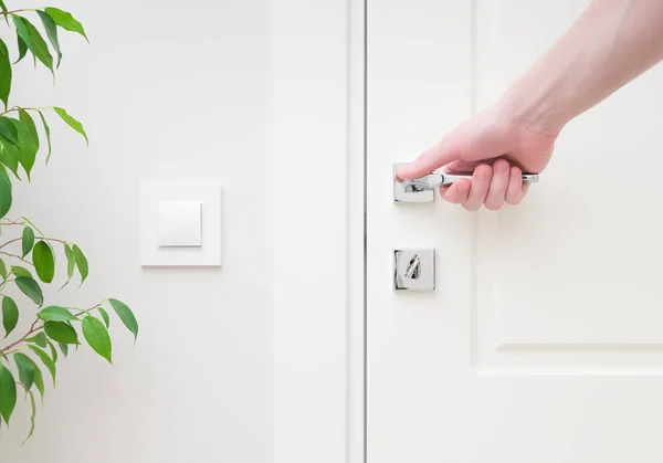 Mano masculina sosteniendo manija moderna de la puerta. Elementos de primer plano del interior del apartamento — Foto de Stock