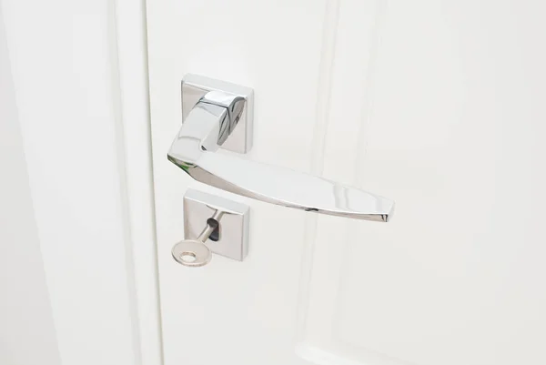 Modern glossy chrome door handle and keyhole with key. Close-up elements of the interior of the apartment — Stock Photo, Image