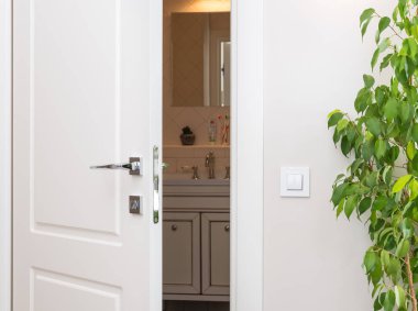 Karanlık bir banyoda açık beyaz kapı. Bir ışık gri duvardaki düğmeye serisi