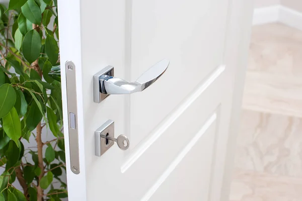 Closeup of door fittings. A white door with modern chrome handles, door lock with key — Stock Photo, Image