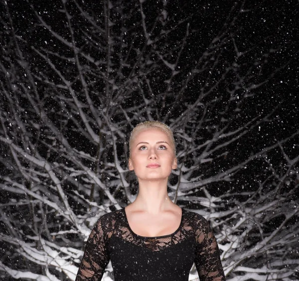 Portret młodej kobiety w snowy nocy w lesie. Pada śnieg — Zdjęcie stockowe