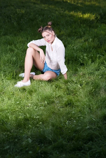 Mulher bonita em roupas casuais na moda sentado na grama — Fotografia de Stock