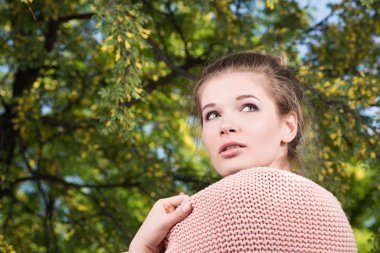 Pembe bir kazak güzel bir Bayan yatay portresi. Çiçekli ağaç arka planda