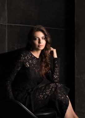 Lüks Bayan siyah dantel elbise bir sandalyede oturuyor. Koyu portre