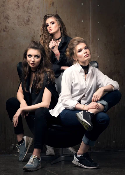 Vertical portrait of three beautiful young women posing on a chair