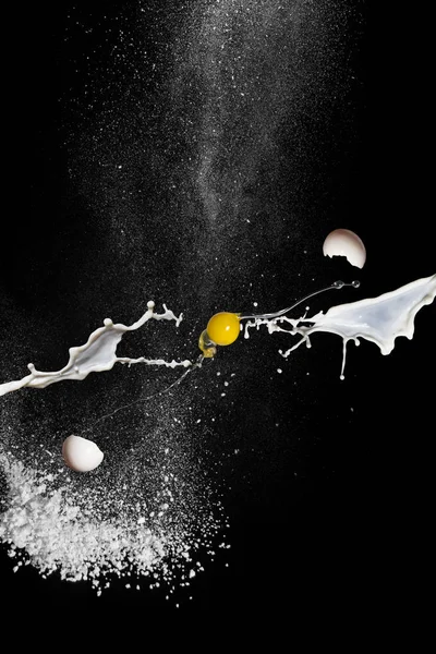 Яйце в польоті, молоко і борошно на чорному тлі. Розсіювання яєчних шкаралуп — стокове фото