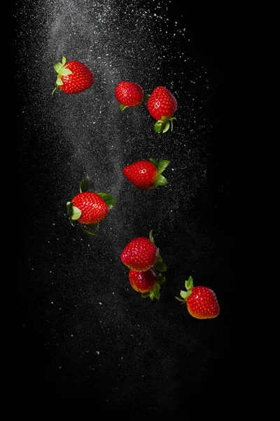 Fragole mature fresche che volano su uno sfondo nero — Foto Stock