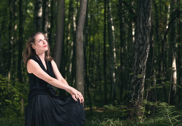 Um homem sozinho com a floresta natural. Retrato de uma jovem mulher em um vestido preto — Fotografia de Stock