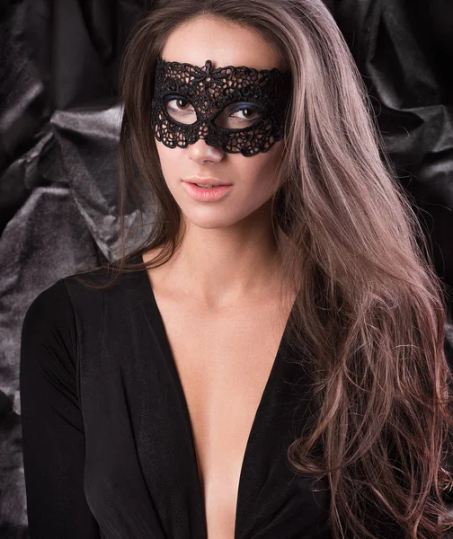 Jovem mulher com máscara de renda preta nos olhos. Vestido preto, cabelo solto — Fotografia de Stock