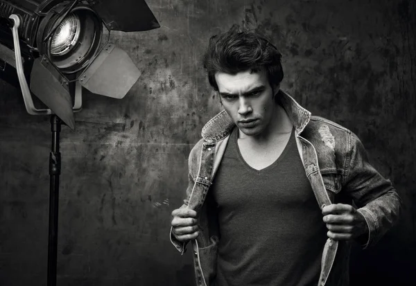 Fashion portrait of a young man in a denim jacket on the set. Black-and-white style — Stock Photo, Image