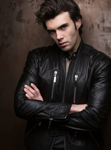 Retrato de un hombre con una chaqueta de cuero negro cerca de la pared —  Fotos de Stock