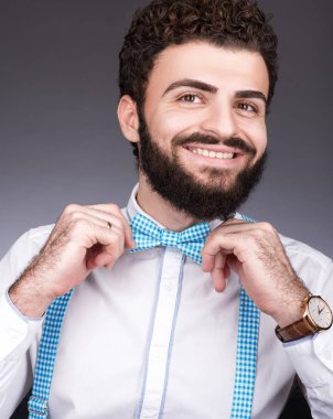 Neşeli genç adam onun papyon ayarlar. Siyah kıvırcık saçlı, bıyık ve sakal