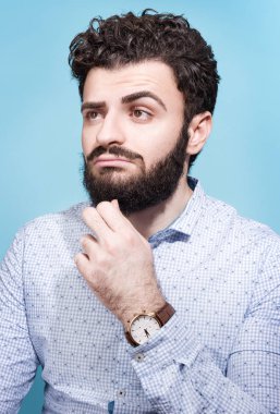 Partret düşünceli delikanlı. Koyu saç, sakal ve bıyık. Işık gömlek ve bilek seyretmek