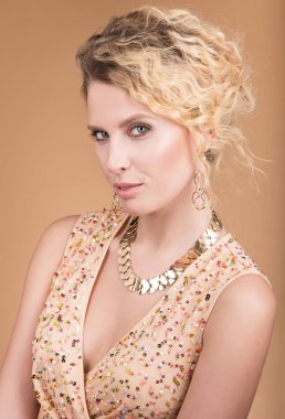 Stüdyo portre bir bej elbise ve altın rengi güzel bir genç kadının