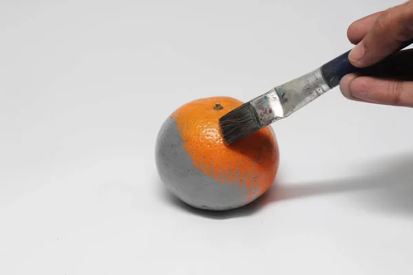 Pintura sobre una fruta monocromática NARANJA con un cepillo aislado — Foto de Stock
