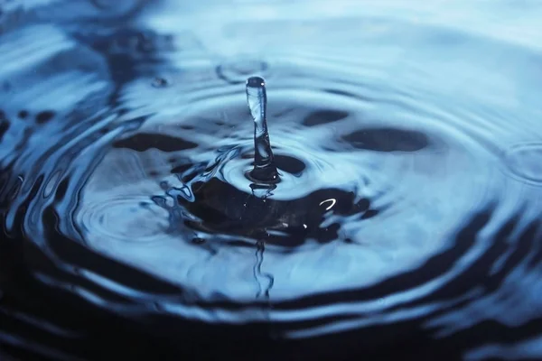 Hermoso chorro de gota de agua en la superficie del agua — Foto de Stock