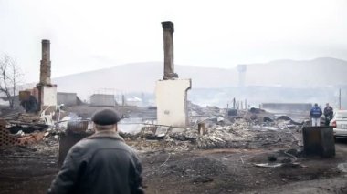 Yaşlı adam bir evde duman yanık kalıntıları geçmiş yürür. Bacalar ve yanmış Ev Isıtma sistemi kalıntıları. Yanık köyün görünümü