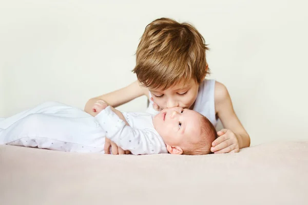 Bebek beyaz pijama onun arkasında yatan. Büyük kardeşi öpücük — Stok fotoğraf