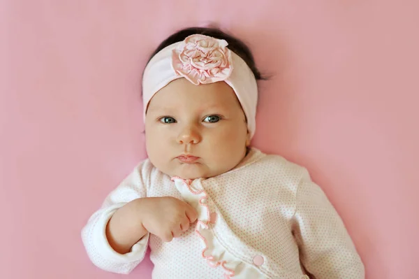 Retrato de um bebê bonito de 2 meses menina vestindo laço flor headband e deitado em cobertor rosa — Fotografia de Stock