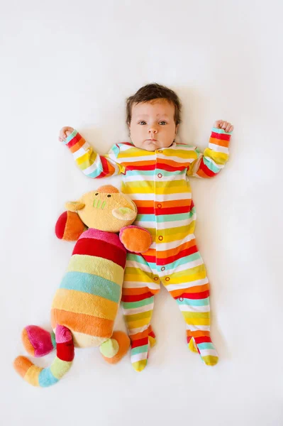 Şirin bebek ile Çizgili Pijama ve yatakta yatarken bir kedi oyuncak renkli — Stok fotoğraf