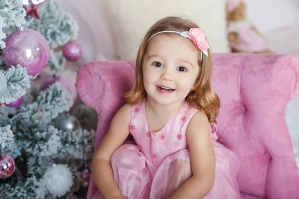 Belle petite fille blonde aux yeux bruns souriant au Nouvel An sur le fond du sapin de Noël — Photo