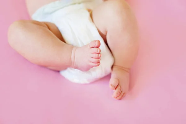 집에서 침대에 누워 기저귀 입고 2 개월 된 아기의 발 — 스톡 사진