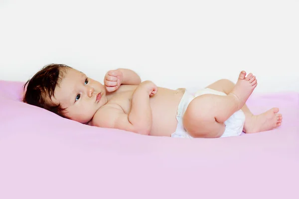 Schattige baby kind kleine jongen meisje liggend op zijn rug en benen houden — Stockfoto