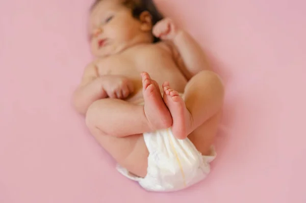 Pies de un bebé de dos meses de edad con pañales acostados en la cama en casa —  Fotos de Stock