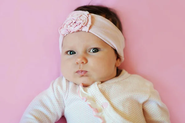 Retrato de um bebê bonito de dois meses menina vestindo laço flor headband e deitado em cobertor rosa — Fotografia de Stock