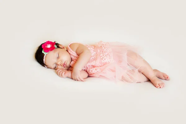 Маленька дівчинка в сукні спить на білій ковдрі — стокове фото