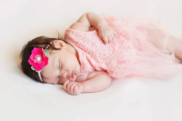Новонароджена дівчина лежить щаслива і розслаблена на ковдрі білого волосся, одягнена в рожевий — стокове фото